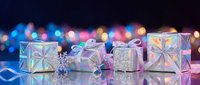 Elegant gift boxes with holographic wrapping and ribbons arranged on reflective surface with colorful bokeh lights creating festive holiday atmosphere.
