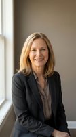 Middle-aged woman with shoulder-length blonde hair, Caucasian ethnicity, wearing dark blazer and gray blouse, smiling confidently by window in office setting for corporate portraits.