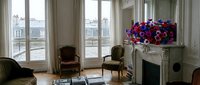 Elegant Parisian apartment interior with ornate fireplace, classic French doors, period furniture and colorful floral arrangement creating sophisticated living space.