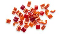 Freshly chopped red and orange bell pepper pieces scattered on white background, isolated for food blogs, recipe sites, and healthy eating content.