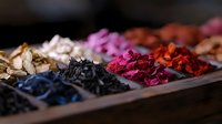 Colorful dried flower petals and herbs arranged in rustic wooden compartment box, natural botanical collection for aromatherapy, tea blending and decoration.