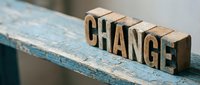 Wooden letterpress blocks spelling CHANGE on a rustic blue painted shelf, symbolizing transformation, growth, and new beginnings in business and life.