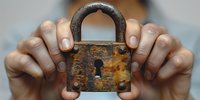 Hands holding vintage rusty padlock with keyhole against blurred background, symbolizing security, privacy protection and data encryption concepts.