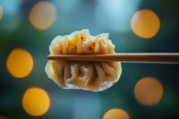 Steamed dumpling held by chopsticks against blurred bokeh lights, showcasing Asian cuisine with pleated wrapper and savory filling.