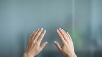 Two hands pressed against frosted glass surface creating intimate human connection moment for wellness and mindfulness concepts.