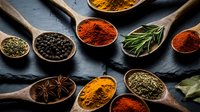 Aromatic spices and herbs in wooden spoons on dark slate background. Colorful seasoning collection with turmeric, paprika, peppercorns and rosemary for cooking.
