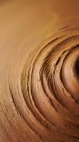 Close-up macro view of natural wood grain rings showing circular growth patterns and organic texture in warm brown tones for carpentry and woodworking projects.