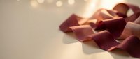 Elegant burgundy satin ribbon flowing gracefully with warm bokeh lights creating romantic atmosphere for luxury gift wrapping and festive celebrations.