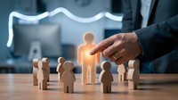 Business hand selecting glowing wooden figure from group representing talent acquisition, leadership choice and human resources management in corporate environment.
