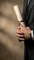 Professional businessman in formal suit holding rolled diploma certificate with red ribbon representing academic achievement and graduation success.