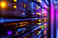 Network server room with colorful LED indicators glowing in dark datacenter. Blurred bokeh lights create modern technological atmosphere for IT infrastructure.