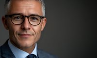 Confident mature businessman with gray hair and glasses against dark background, professional portrait for corporate profile or leadership concept.