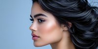 Young Asian woman with flowing black hair and professional makeup in profile view against blue background, showcasing beauty and cosmetic styling.