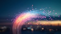 Magical glowing particles and light trails form an arc against blurred city lights at dusk, creating ethereal atmosphere with pink and blue bokeh effect.
