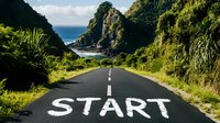 Coastal road with START painted on asphalt leading to dramatic ocean cliffs and lush green vegetation, symbolizing new beginnings and journey ahead.