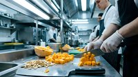 Professional chef preparing fresh butternut squash in commercial kitchen environment for culinary food preparation and cooking operations.
