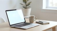 Clean minimalist workspace with open laptop displaying blank white screen on wooden desk alongside coffee mug and notebook for productivity and remote work.