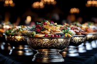 Elegant silver bowls filled with colorful appetizers and fresh garnishes on dark tablecloth, selective focus with blurred background creating luxurious catering atmosphere.