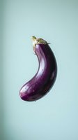 Fresh purple eggplant with green stem isolated on light blue background. Suitable for food, cooking, recipe, nutrition, organic produce, and culinary design projects.