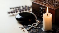 Spa wellness setup with burning candle, lavender sprigs, essential oil bowl and wooden aromatherapy box for relaxation and self-care rituals.