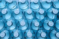 Rows of plastic water bottles in blue tones viewed from above create geometric pattern. Clean drinking water concept for healthy lifestyle and hydration.