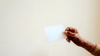 Henna-decorated hand holding blank white card against neutral background, suitable for wedding invitations, cultural event promotions, and festive greetings.