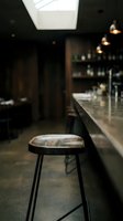 Modern bar stool with leather seat in contemporary restaurant interior with skylight, counter seating, and ambient lighting for hospitality design projects.