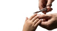 Professional manicure process with metal cuticle scissors trimming fingernails on white background for beauty salon and nail care services.