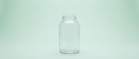 Empty clear glass jar on mint green background, isolated container for storage, packaging, or design mockup purposes.