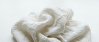 Crumpled white cotton textile with soft folds and wrinkles isolated on light background, suitable for fabric, laundry, and design projects.