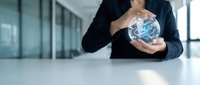 Businessman holding glowing digital globe with network connections in modern office environment representing global business technology and connectivity.
