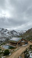 Modern cabin with solar panels nestled in snow-capped mountain valley, sustainable architecture and renewable energy for eco-friendly living and off-grid homes.