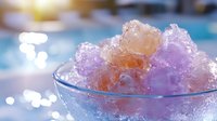 Colorful shaved ice dessert with purple and orange syrup in glass bowl against blurred summer background with sparkling bokeh lights and sunflare.