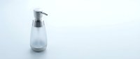 Modern glass soap dispenser with chrome pump on clean white surface for bathroom and kitchen hygiene products.