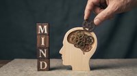 Man's hand pouring gears into wooden head silhouette next to mind wooden blocks. Concept for mental health, psychology, intelligence, creativity, problem solving, business strategy.