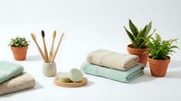 Spa wellness setup with folded towels, bamboo toothbrushes, soap, reed diffuser and potted plants on white surface for relaxation and self-care routines.
