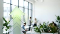 Green arrow pointing upward symbolizes business growth, success, and positive financial progress in modern office environment with blurred team.