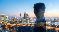 Double exposure silhouette of businessman overlaid with illuminated city skyline at dusk, representing urban professional success and corporate vision.