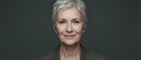Senior woman with short gray hair and warm smile against neutral background, professional portrait.