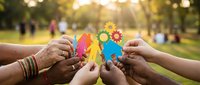 Diverse hands holding colorful paper cutouts with gears in outdoor park setting, representing teamwork, collaboration, and unity in business and community projects.