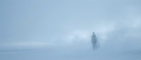 Solitary figure standing in dense fog and mist during winter, creating atmospheric and moody landscape for conceptual, editorial, and environmental storytelling projects.