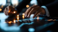 Male hands typing on illuminated keyboard in dark office with bokeh lights creating moody atmosphere. Focus on fingers with shallow depth of field and blue backlight glow.