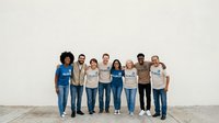 Diverse group of men and women standing together against white wall, wearing casual clothing, representing teamwork, unity, and community collaboration for corporate, nonprofit, or social initiatives.