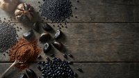 Autumn spices and ingredients arranged on rustic wooden background with pumpkins, cocoa powder, coffee beans and seasonal decorative elements for cooking.