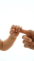 Newborn baby hand gripping adult finger on white background, symbolizing trust, love, and family bond.