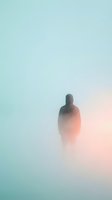 Silhouetted figure standing in dense fog with gradient background transitioning from turquoise to soft pink, creating moody atmospheric effect for conceptual and editorial design projects.