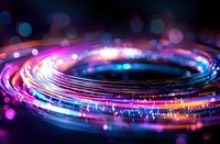 Glowing spiral light trails with vibrant pink, blue and orange colors against dark background create dynamic motion effect with blurred bokeh circles.