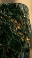 Raw green mineral specimen with golden metallic veins and crystalline formations for geology education and natural history collections.