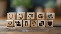 Wooden dice with emotional intelligence and communication symbols arranged in row on rustic table surface. Social skills and empathy concept for coaching and training.