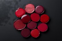 Red and burgundy lipstick palette swatches arranged on dark background, showcasing rich shades from crimson to deep wine for makeup artistry.